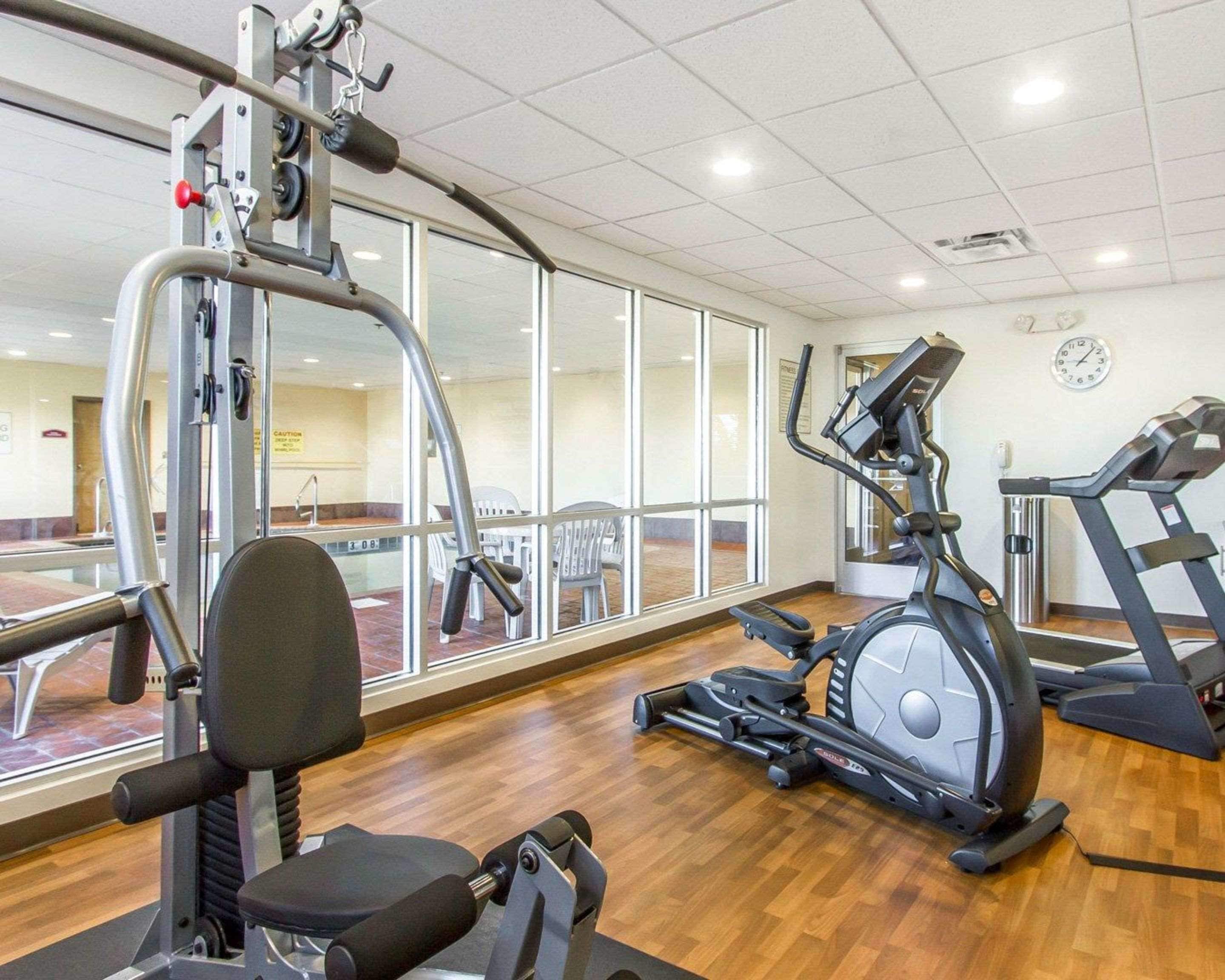 A gym with cardio machines, a weight bench, and a mirrored wall.