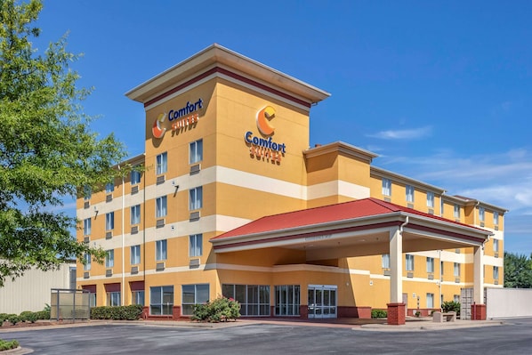 A Comfort Suites hotel with a red roof, multiple floors, and a covered entrance.