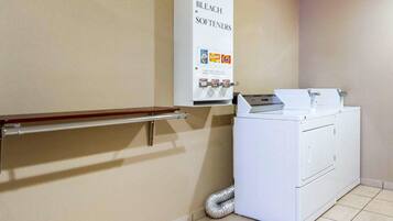 A laundry room with a washing machine, a soap and bleach dispenser, and a handrail.