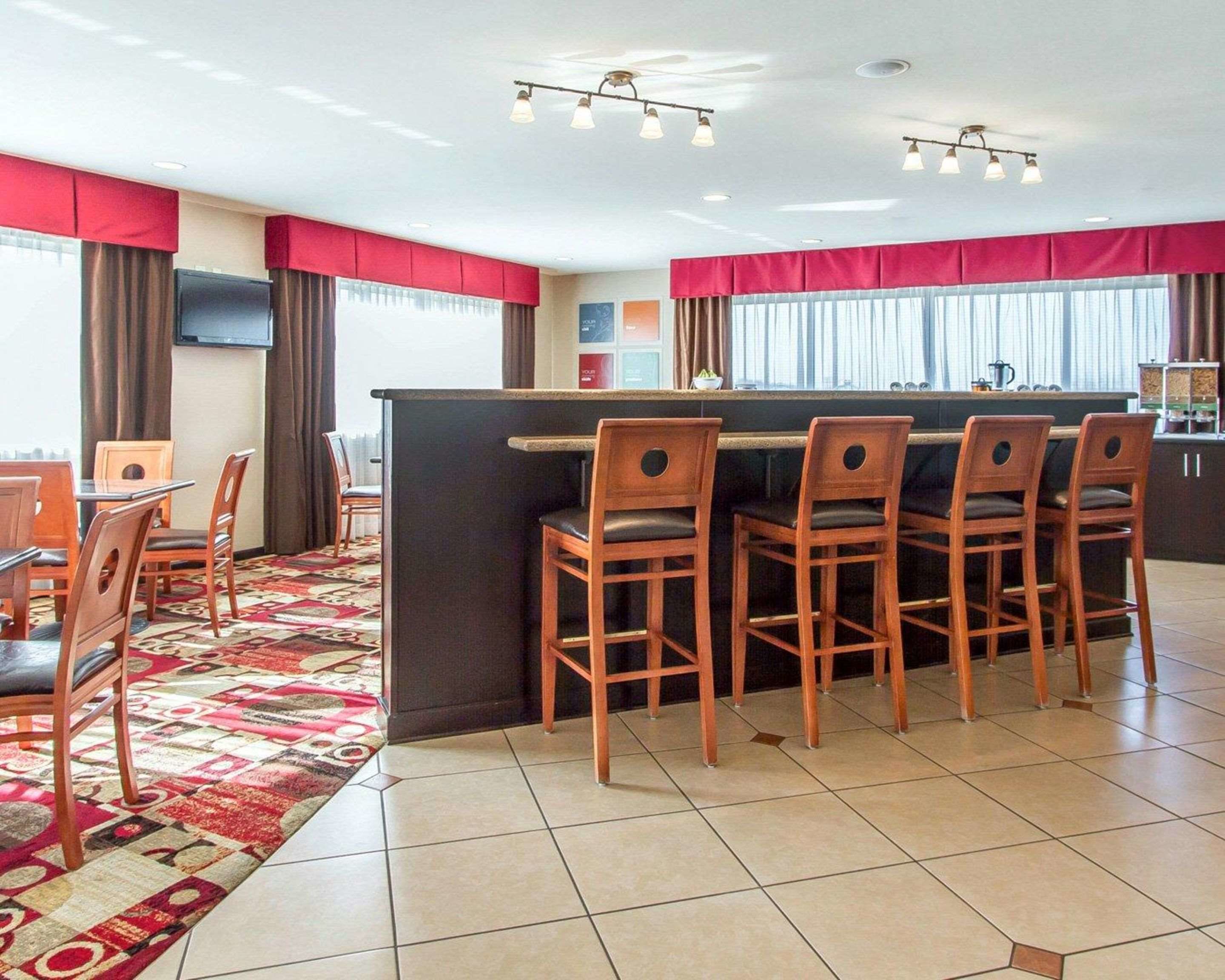 A hotel room with a dining area, a bar, and a TV mounted on the wall.