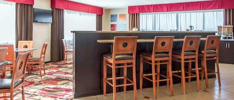 A hotel room with a dining area, a bar, and a TV mounted on the wall.