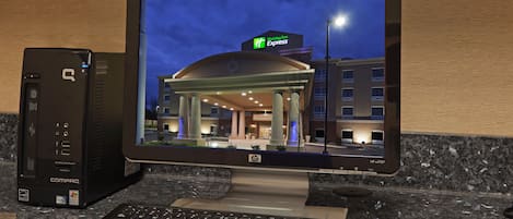 Un vestíbulo de hotel con un amplio atrio, una recepción y vistas del exterior del edificio por la noche.