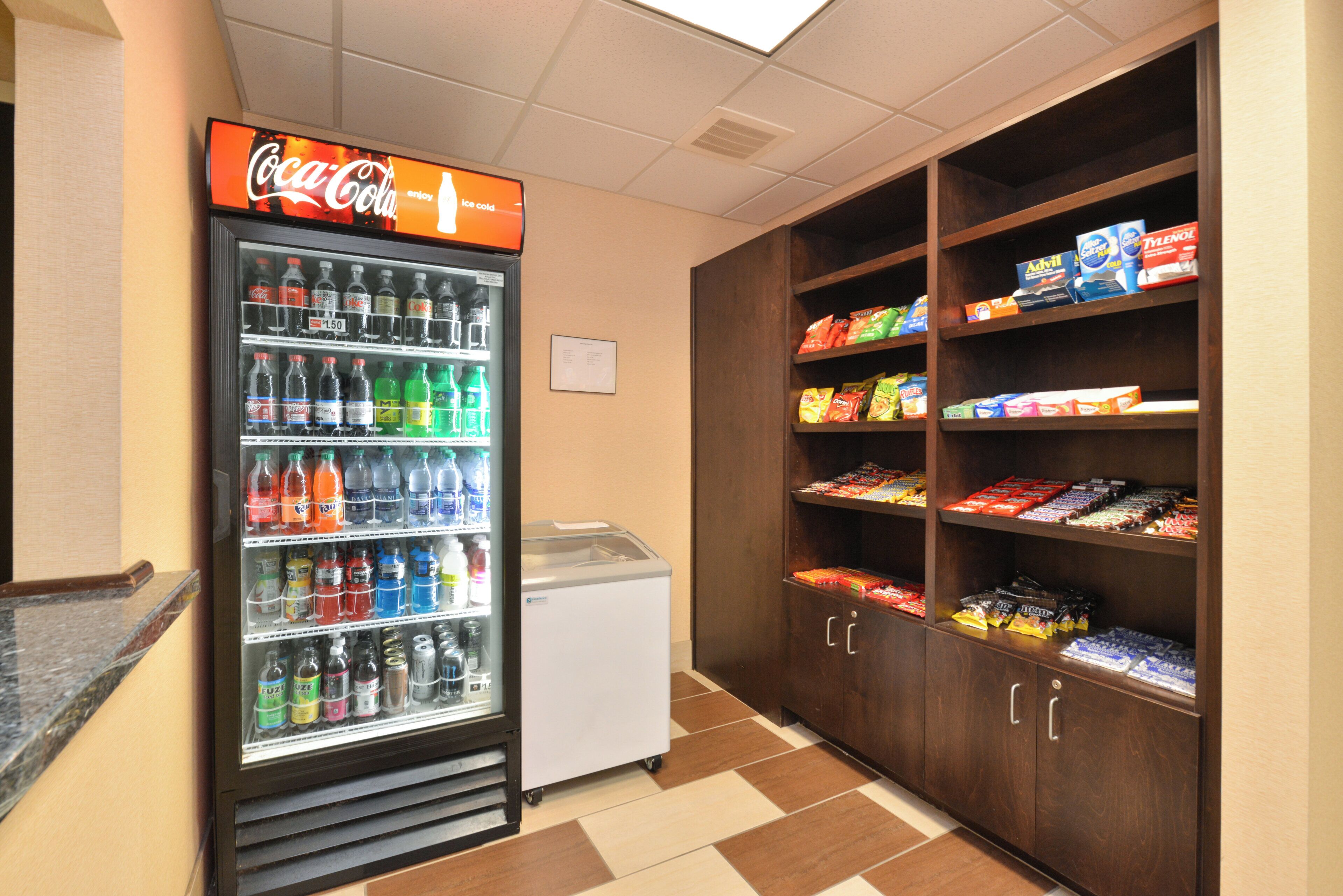 Un distributeur automatique orné d’une enseigne Coca-Cola, un réfrigérateur et une étagère remplie de collations.