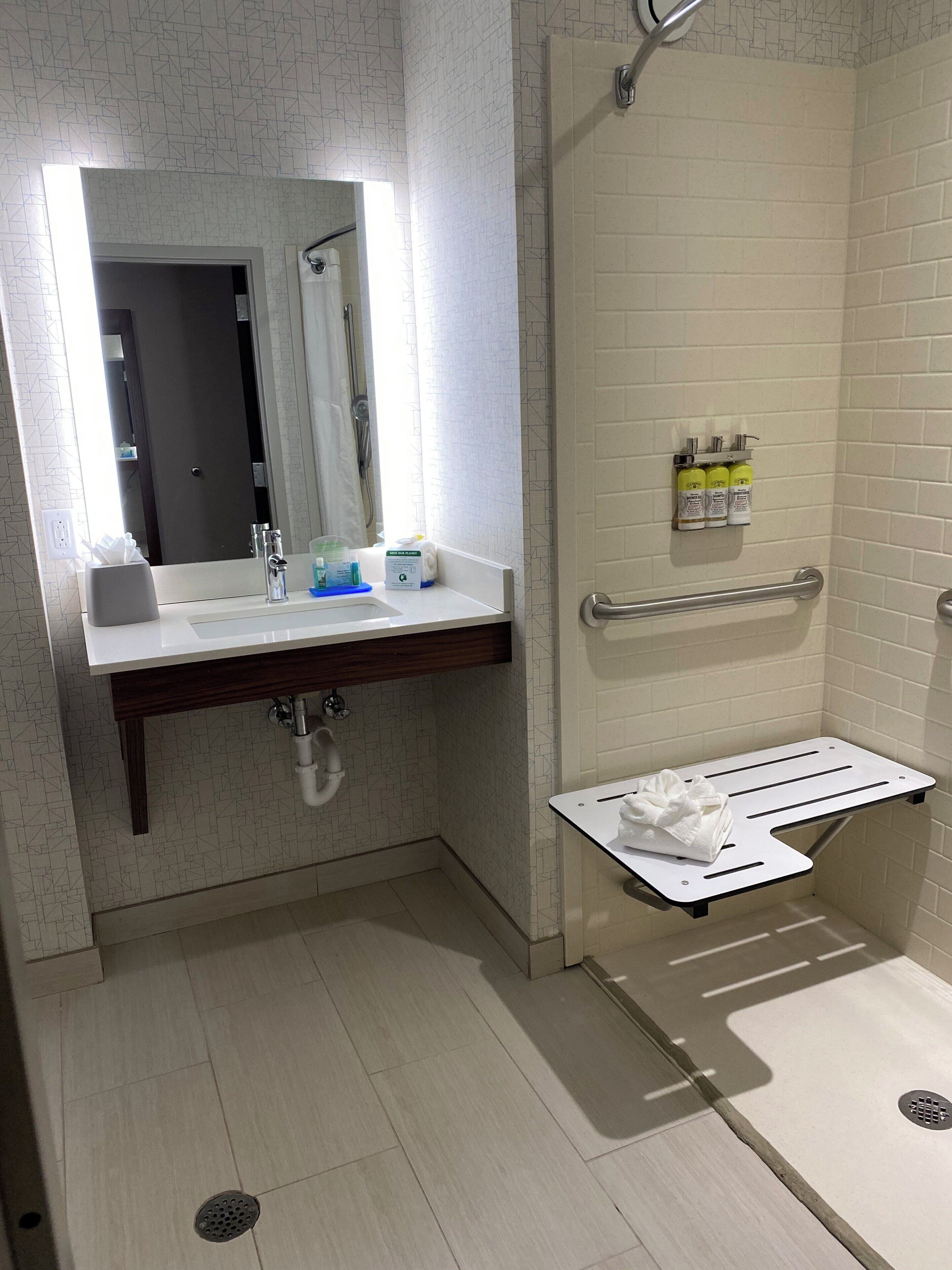 Une salle de bain équipée d’un miroir, d’un lavabo, d’un porte-serviettes et d’une zone douche.