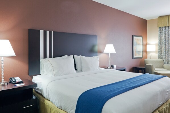 Habitación de hotel con una cama grande, dos mesitas de noche, una silla y un escritorio con teléfono.
