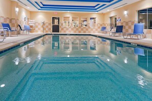 En swimmingpool med liggestole og en dør til omklædningsrum.