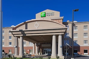 Un bâtiment de l’hôtel Holiday Inn Express avec une entrée centrale, des colonnes et un ciel bleu dégagé.