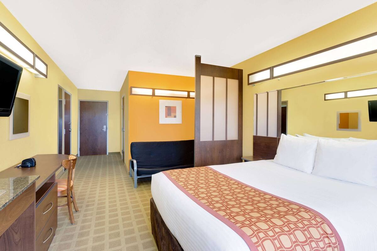A hotel room with a bed, a desk, a chair, and a television.