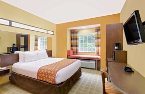 Une chambre d’hôtel avec un grand lit, un bureau, une télévision et une fenêtre avec des rideaux.