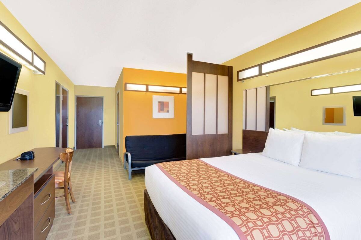 A hotel room with a bed, a desk, a chair, and a television.