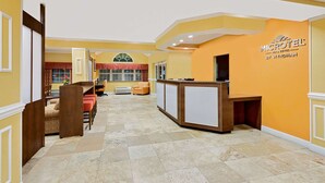 A hotel lobby with a reception desk, seating area, and a large window with a view. - Microtel Inn & Suites by Wyndham Princeton (Princeton)