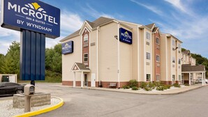 A Microtel Inn & Suites building with a beige exterior, a prominent sign, and a parking area with a meter. - Microtel Inn & Suites by Wyndham Princeton (Princeton)