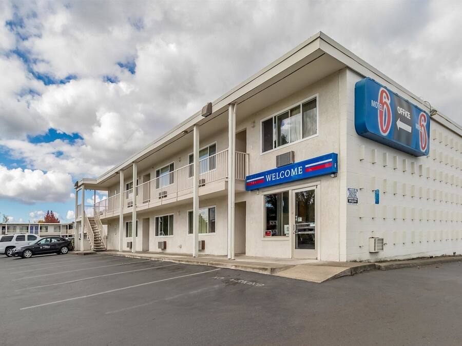 A motel with a 'Welcome' sign, a parking lot, and a 'No Parking' sign on the street.