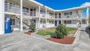 A multi-story motel with a central courtyard, white railings, and a Pepsi vending machine.