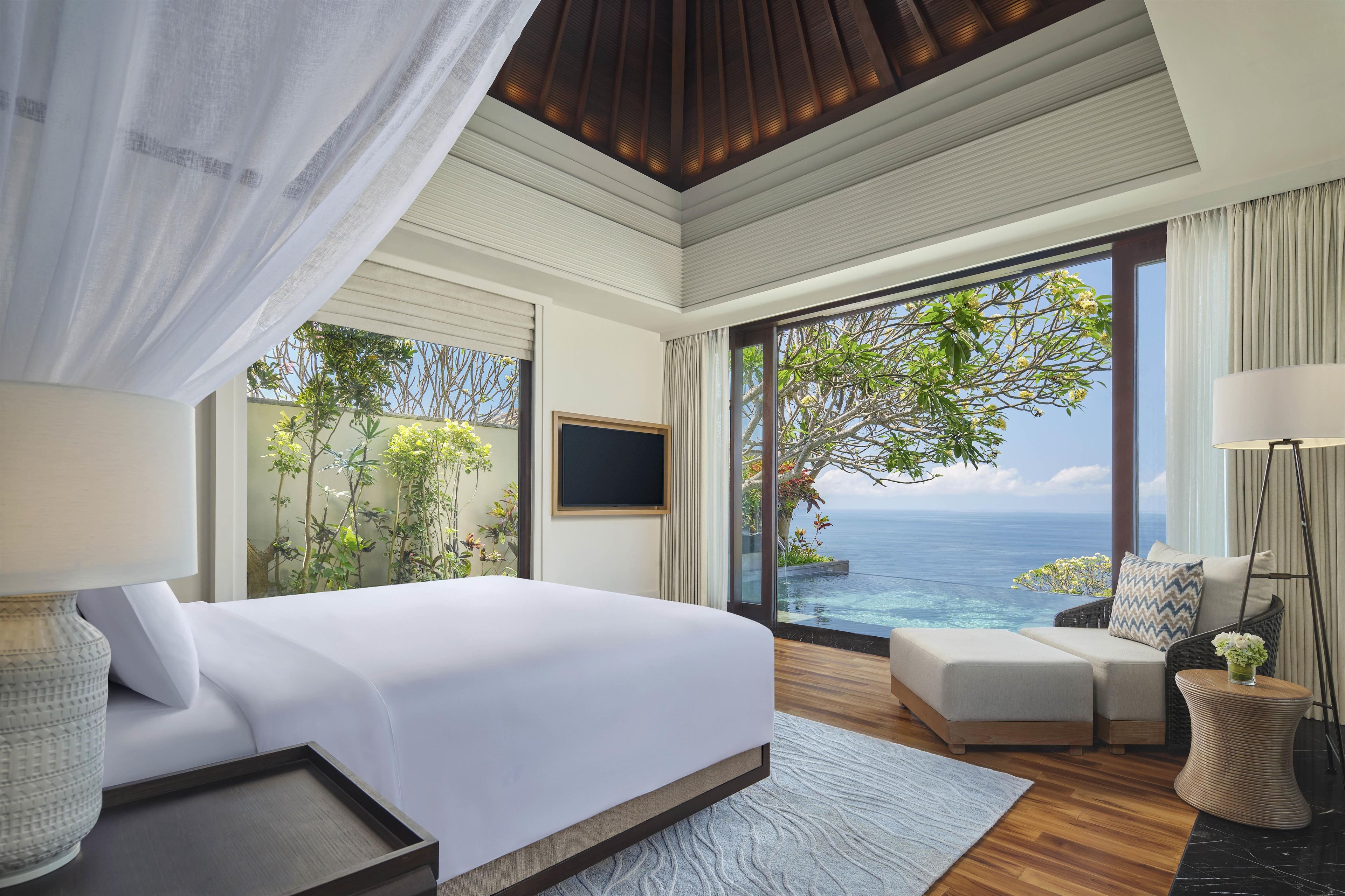 Une chambre spacieuse avec un grand lit, un coin salon et une vue sur l’océan.