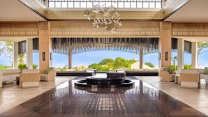 A spacious lobby with a central circular seating area, large windows offering a view of the sea, and a modern chandelier. - Umana Bali, LXR Hotels & Resorts (Ungasan)