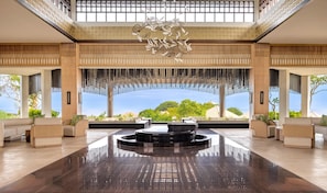 A spacious lobby with a central water feature, seating areas, and large windows offering a view of the sea. - Umana Bali, LXR Hotels & Resorts (Ungasan)