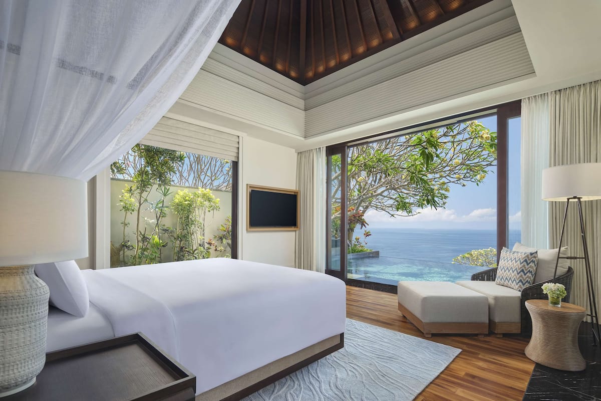 A bedroom with a large bed, a TV, and a view of the ocean.