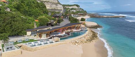 A coastal resort with a swimming pool, beach, and cliffside views.