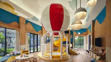 Children can play and explore in this indoor play area featuring a central play structure with a slide and a netted enclosure.