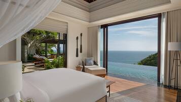 A modern bedroom with a large bed, a view of the ocean, and a balcony with outdoor furniture.