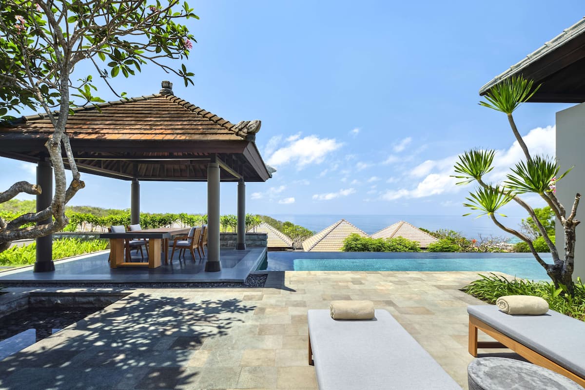 A poolside area with a gazebo, lounge chairs, and a view of the ocean.