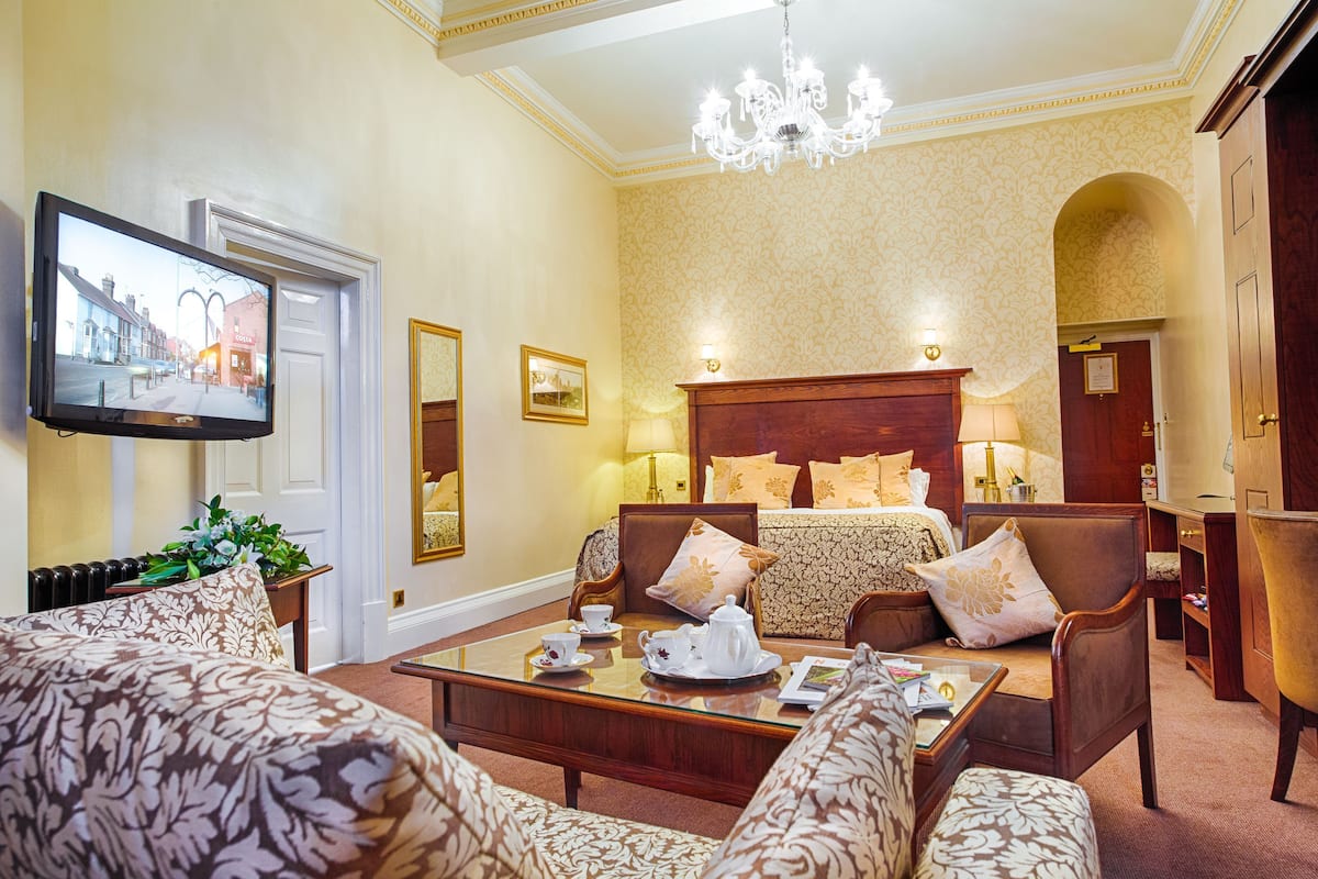 Ein Hotelzimmer mit einem Bett, zwei Sofas, einem Couchtisch, einem Fernseher und einer Deckenleuchte.