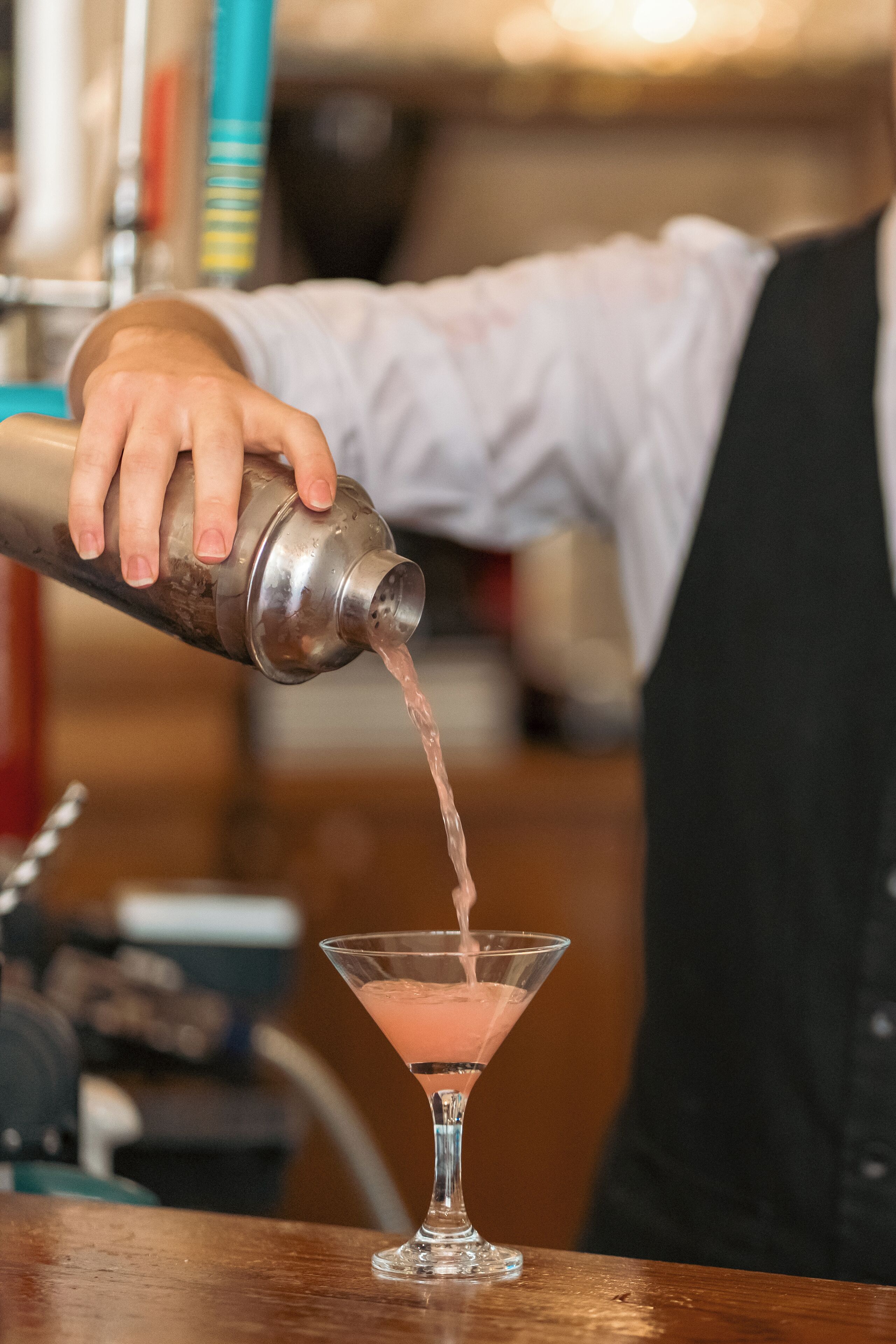Ein Barkeeper gießt ein Getränk in ein Martini-Glas.