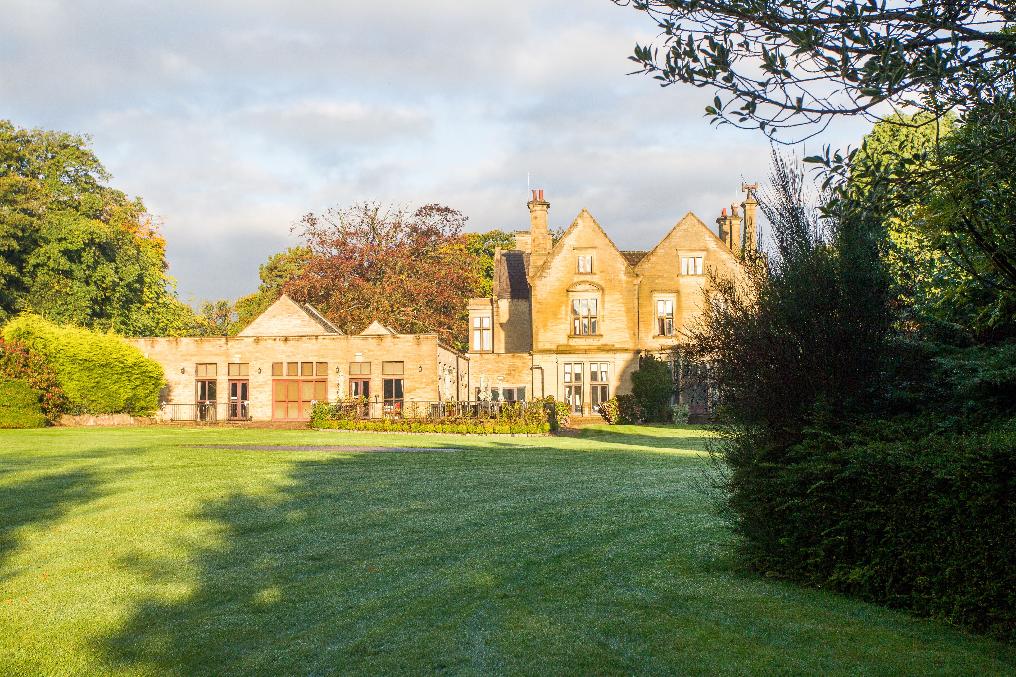 A large, historic building with multiple chimneys and a well-maintained lawn.