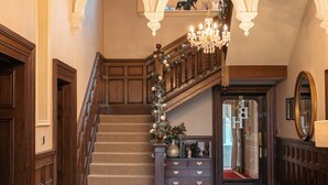Eine prachtvolle Treppe mit einer Chandelüster, Holzvertäfelung und einem Spiegel.