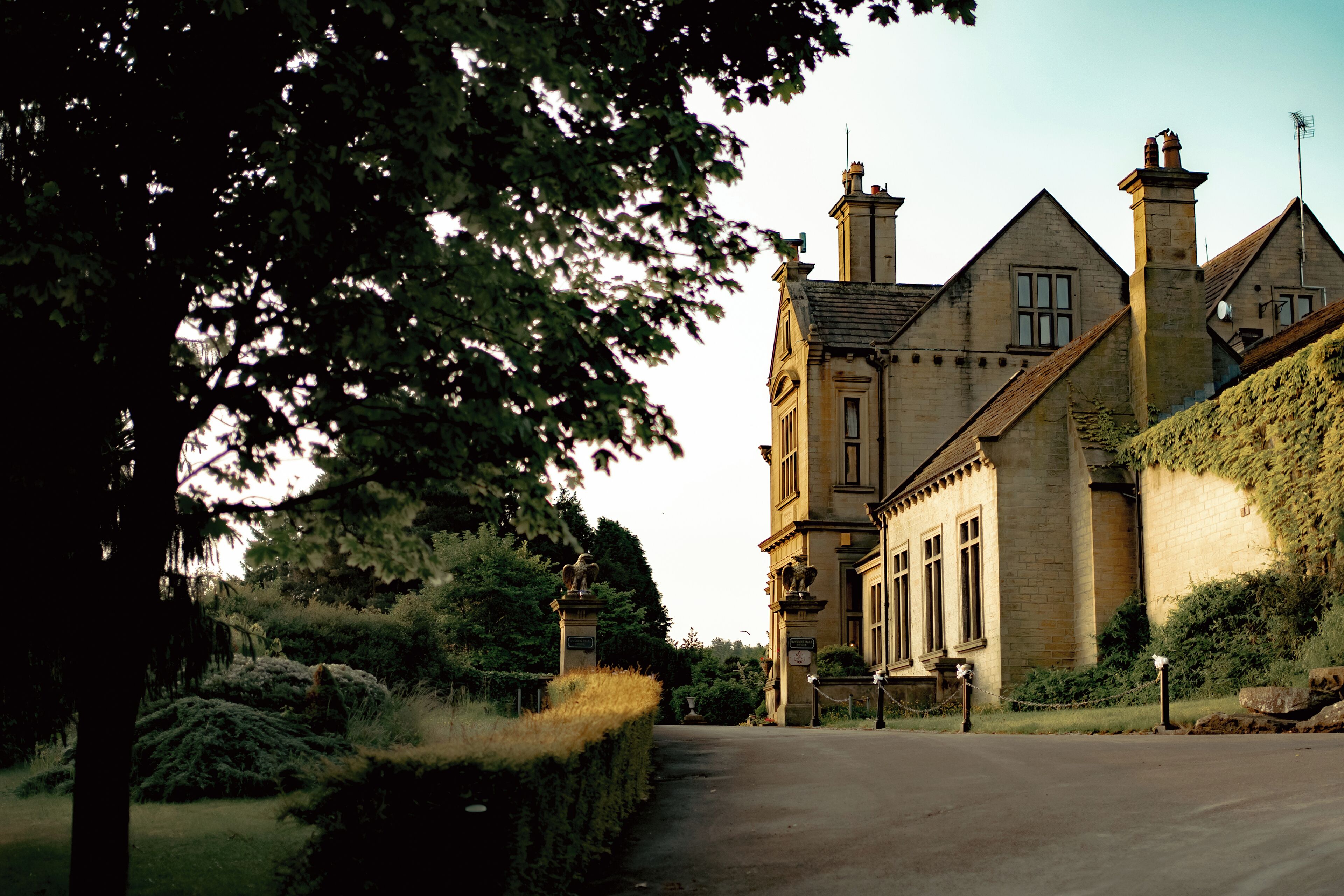 A historic building with a prominent entrance, a stone facade, and a well-maintained garden.