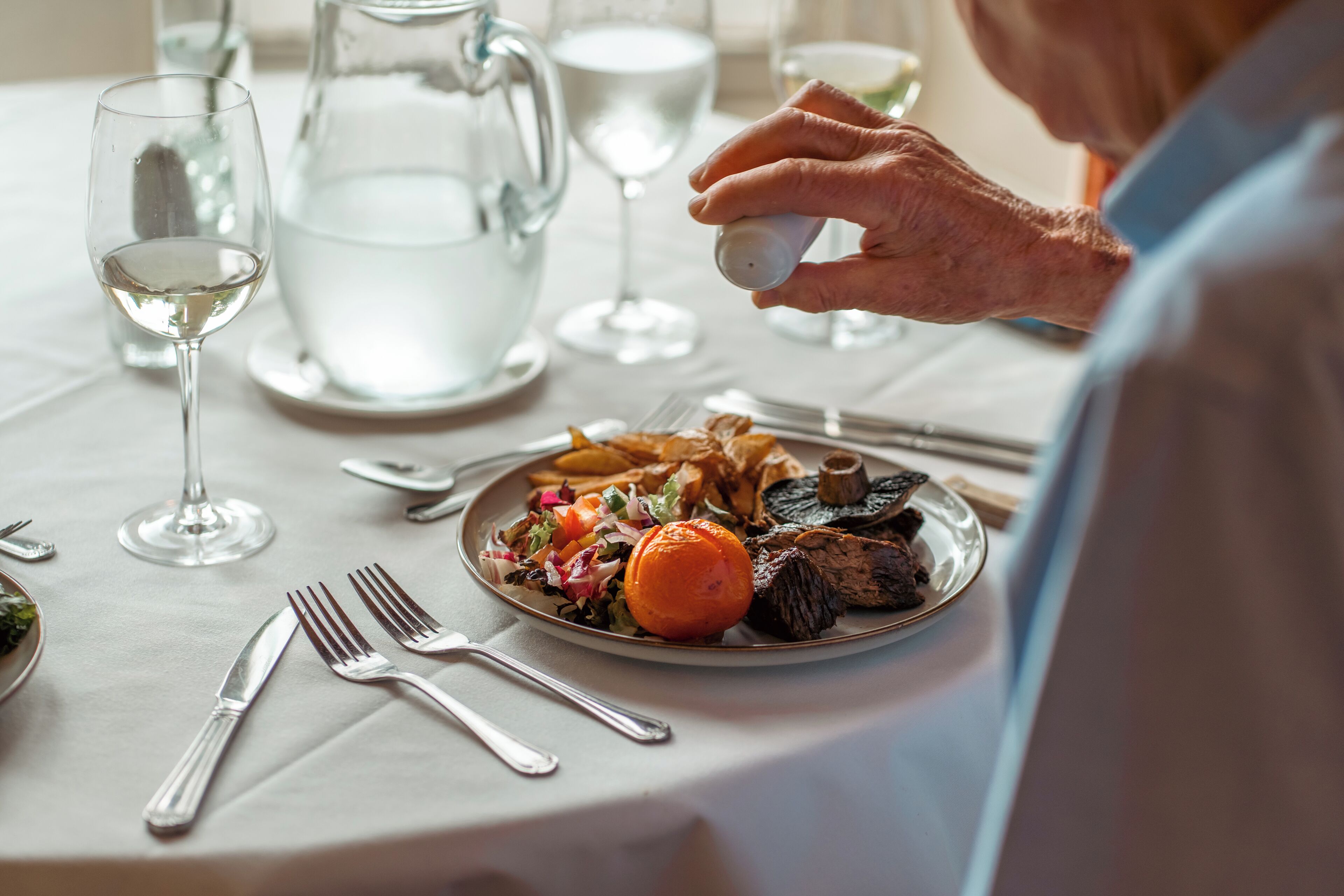 A dining table with a plate of food, a pitcher, and a glass of water.