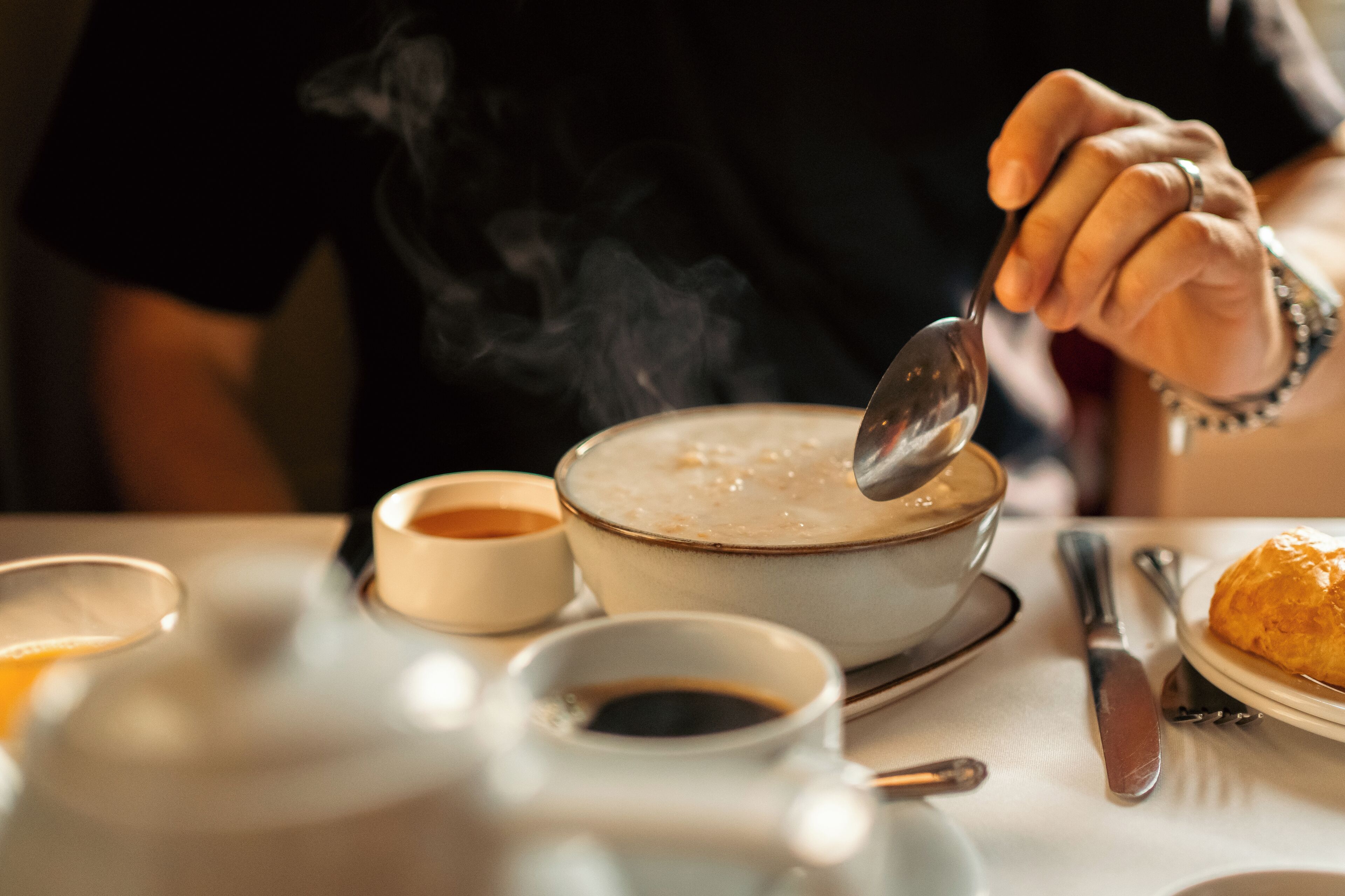 Un tavolo da pranzo con una ciotola di zuppa, una tazza di caffè e un piatto con un dolce.
