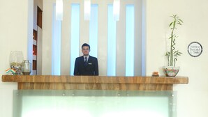 A reception desk with a modern design, a large mirror, and a potted plant. - Regency Hotel Malabar Hill (Mumbai)