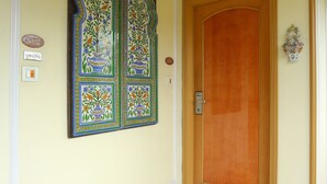 A hallway with a wooden door, a decorative wall panel, and a marble floor. - Regency Hotel Malabar Hill (Mumbai)