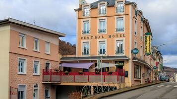 Een meerlaags hotel met een centrale ingang, balkons en een overdekt terras.