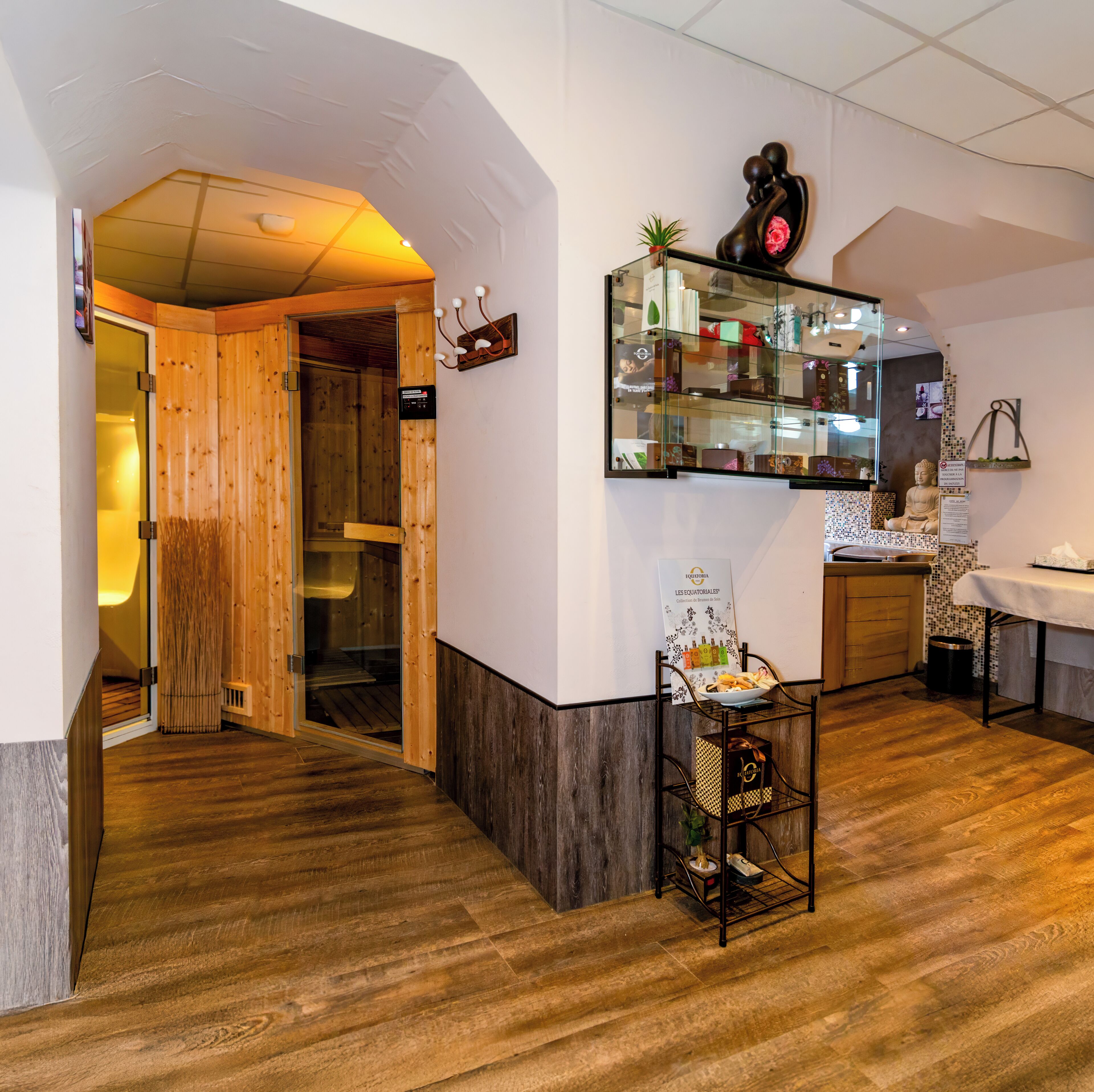 A hotel lobby with a wooden reception desk, a glass display case with various items, and a Buddha statue.