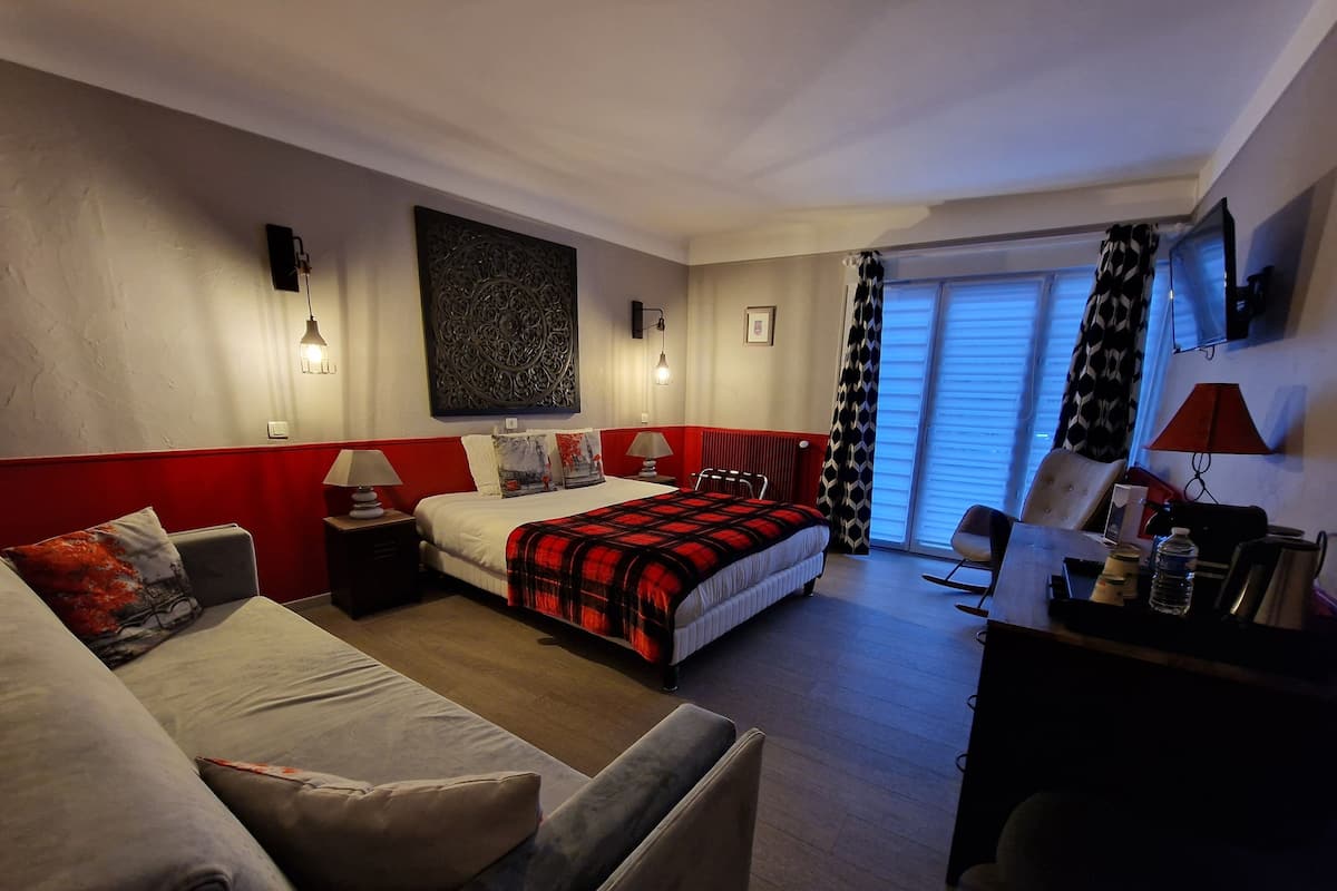 A hotel room with a bed, a sofa, a desk, and a chair.