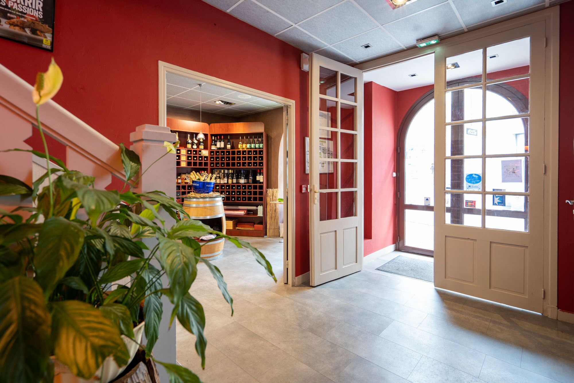 Un hall de hotel con una pared roja, un botellero de madera y un amplio arco.
