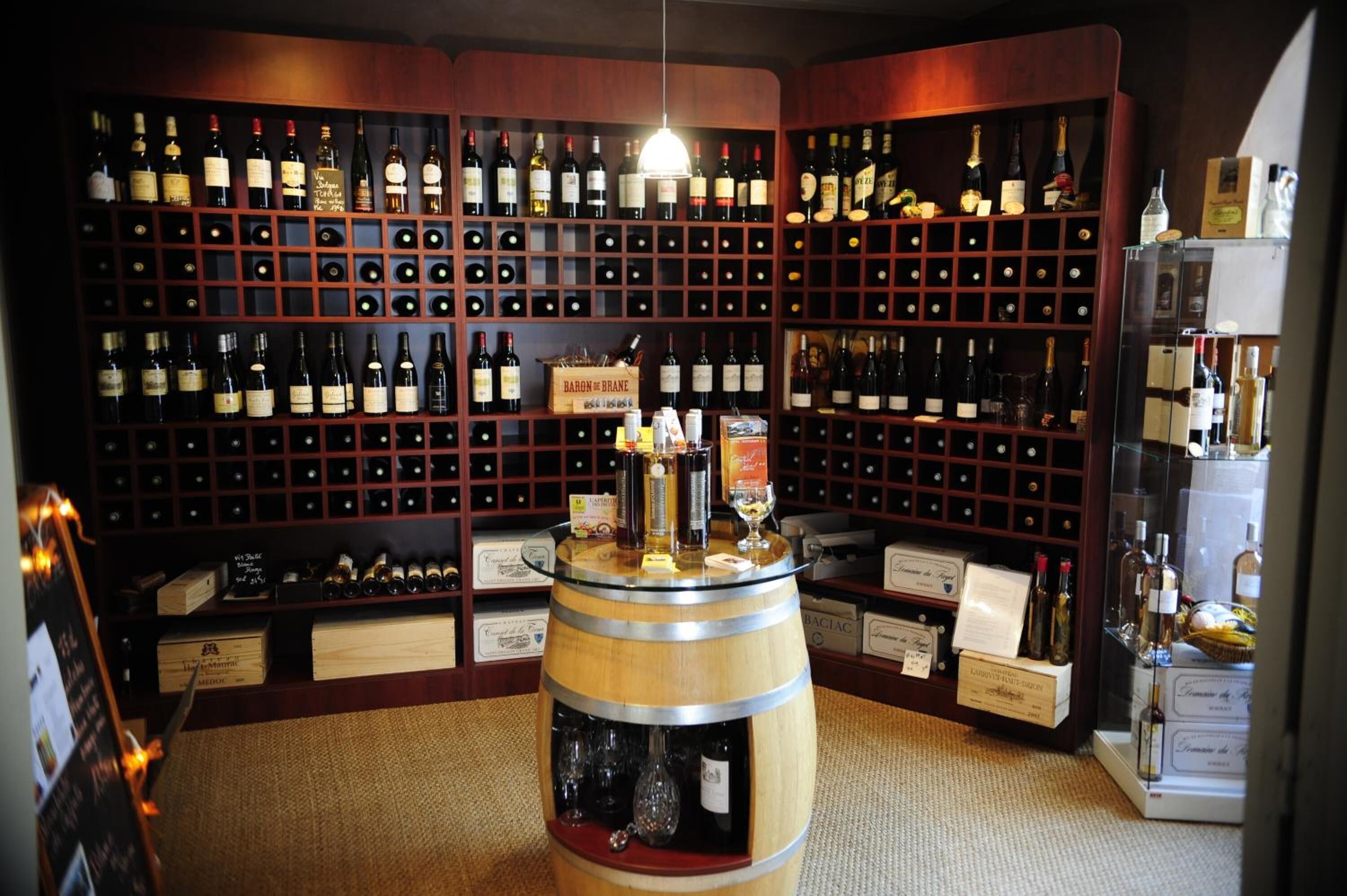 Una cava con estantes de madera llenos de botellas de vino y una exhibición central de barricas.