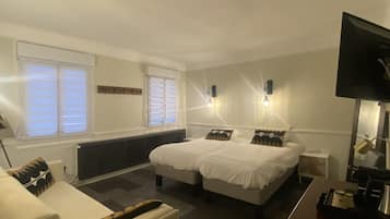Habitación de hotel con dos camas, un sofá, una mesita y un televisor.