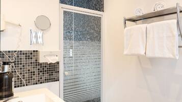 A modern bathroom with a white sink, a glass shower enclosure, and a towel rack.