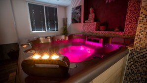 A hot tub with a control panel, a window, and a Buddha statue in the background. - Logis Central Hôtel & Spa (Bort-les-Orgues)