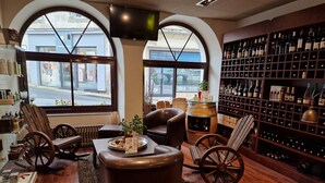 A cozy interior with leather chairs, a wine rack, and a view of the street outside. - Logis Central Hôtel & Spa (Bort-les-Orgues)