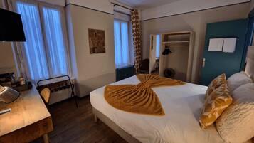 A hotel room with a bed, a desk, a chair, a wardrobe, and a television.
