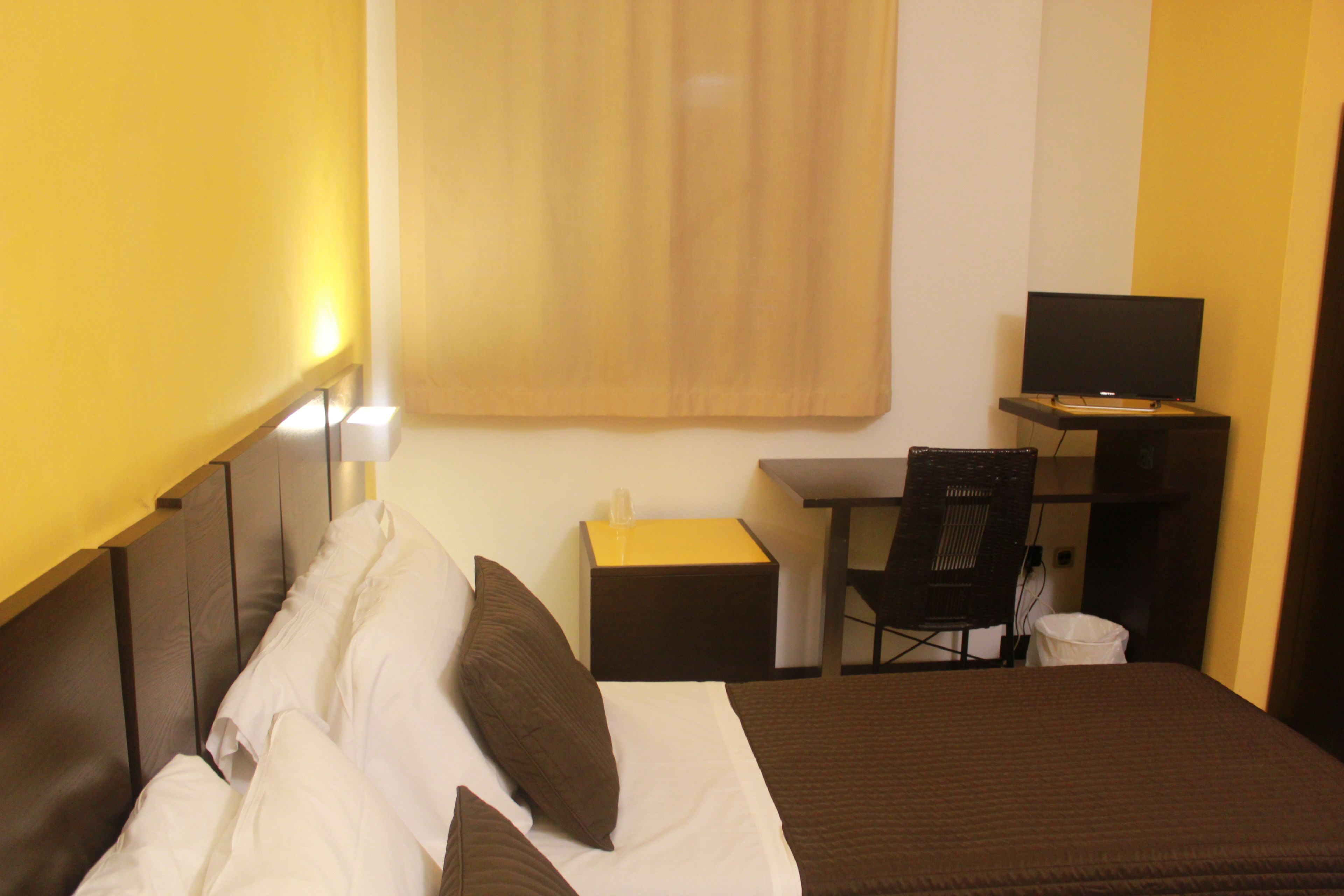Een hotelkamer met een bed, bureau, stoel en televisie.