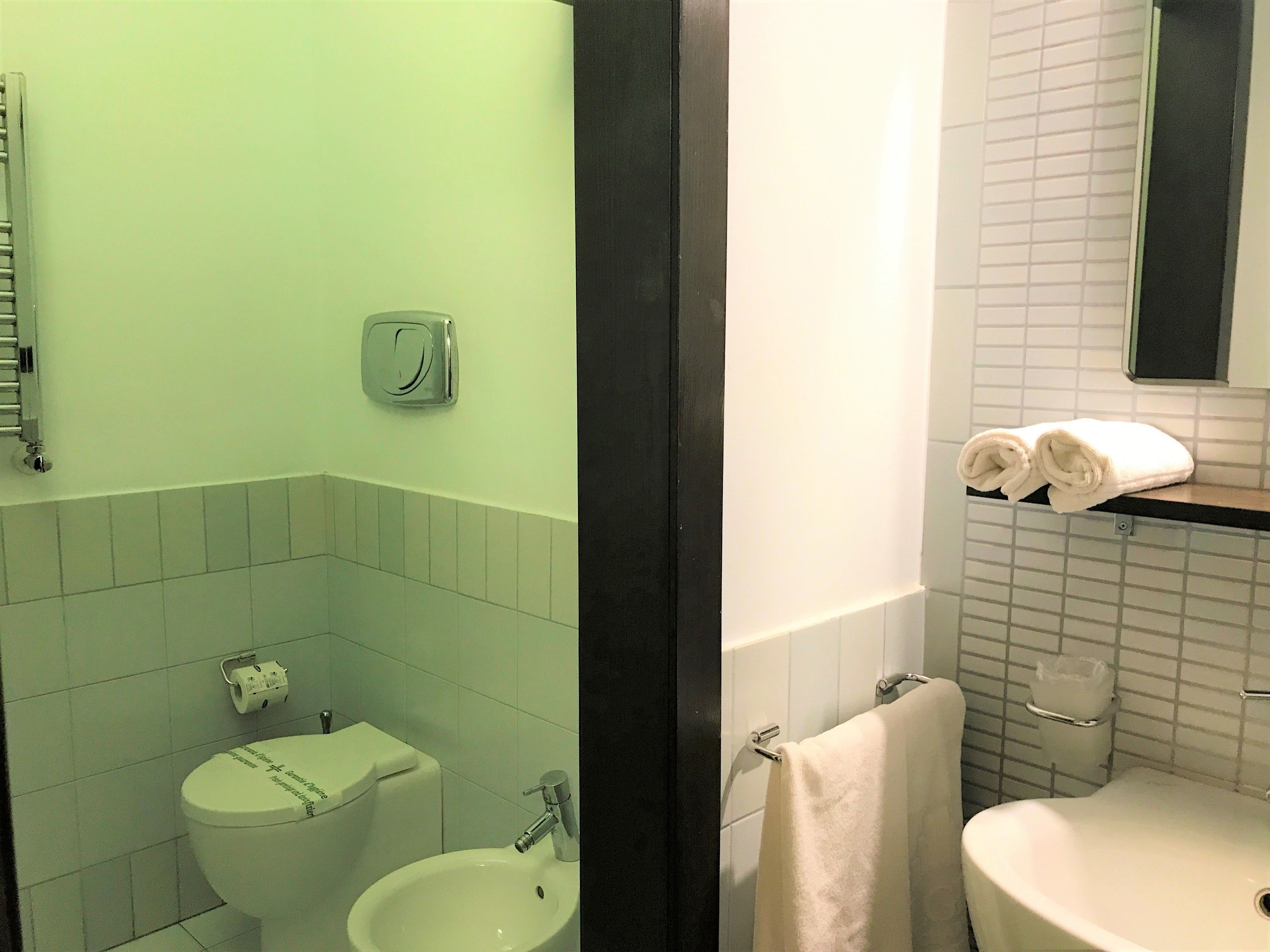 A bathroom with a toilet, bidet, sink, and towel rack.