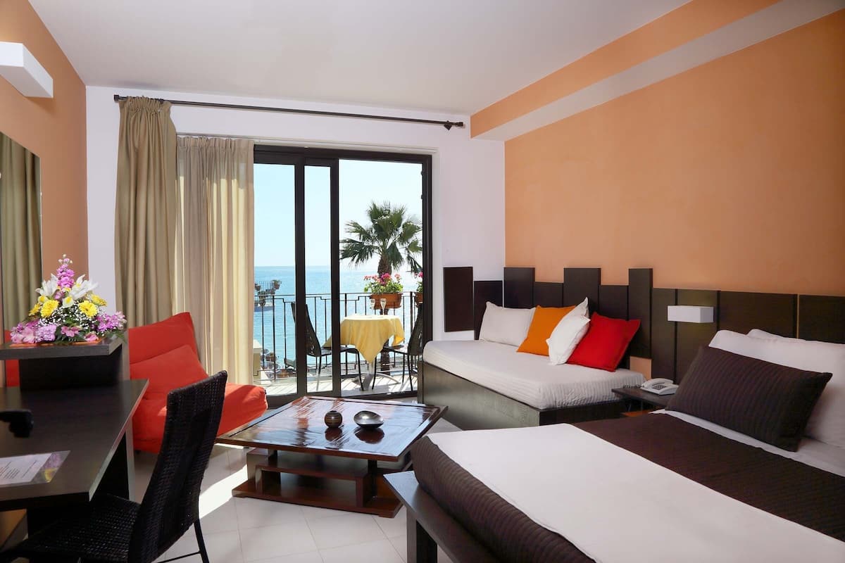 Une chambre d’hôtel avec un balcon, un coin repas et un lit agrémenté de plusieurs oreillers.