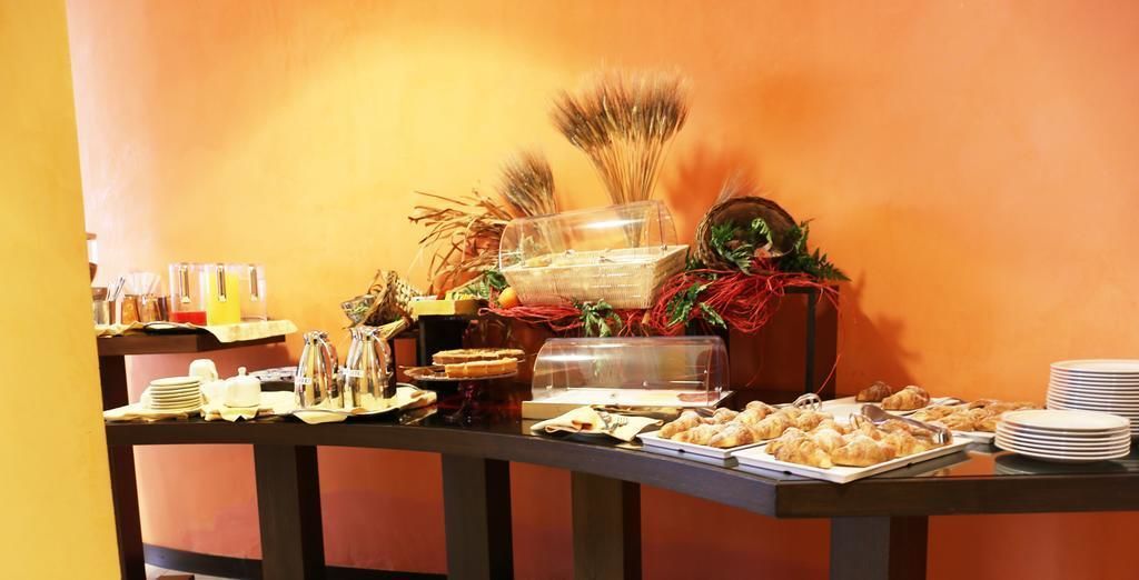 Une table de buffet garnie de divers plats et un coin café, le tout installé devant un mur jaune.