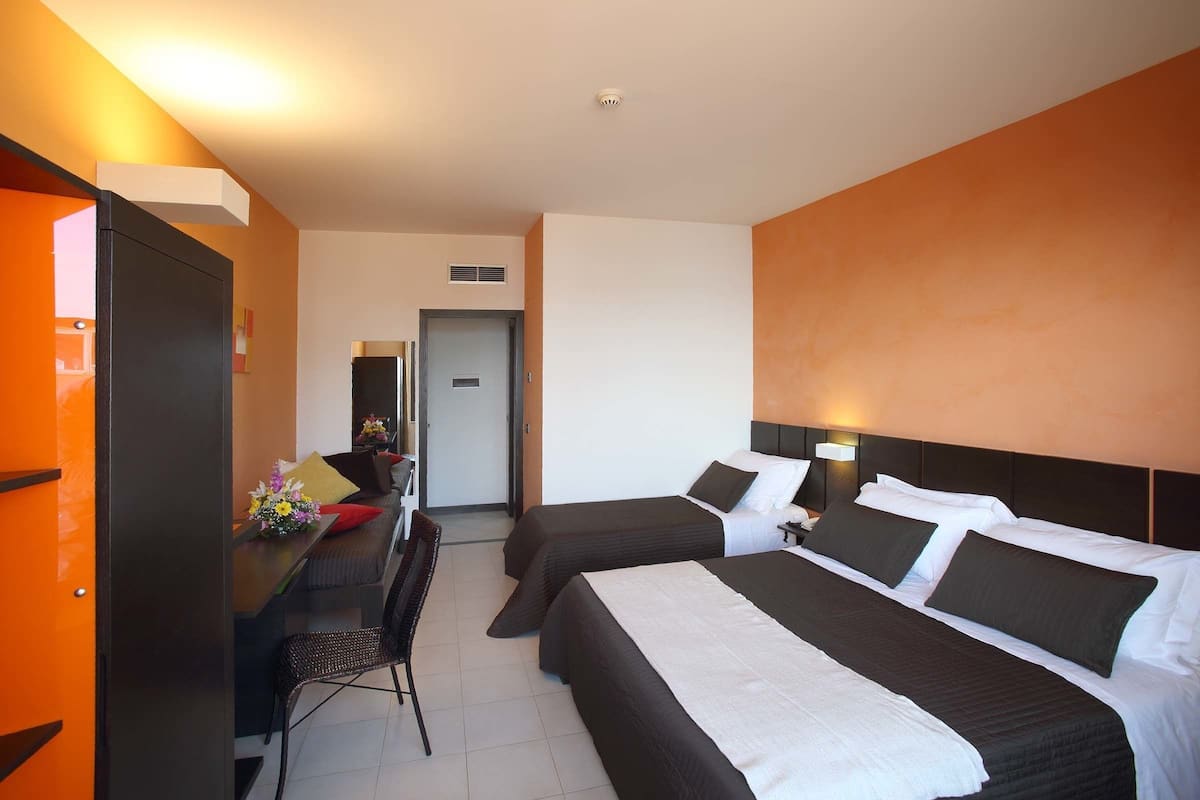 Une chambre d’hôtel avec deux lits, un bureau avec une chaise et une porte donnant sur une salle de bain.